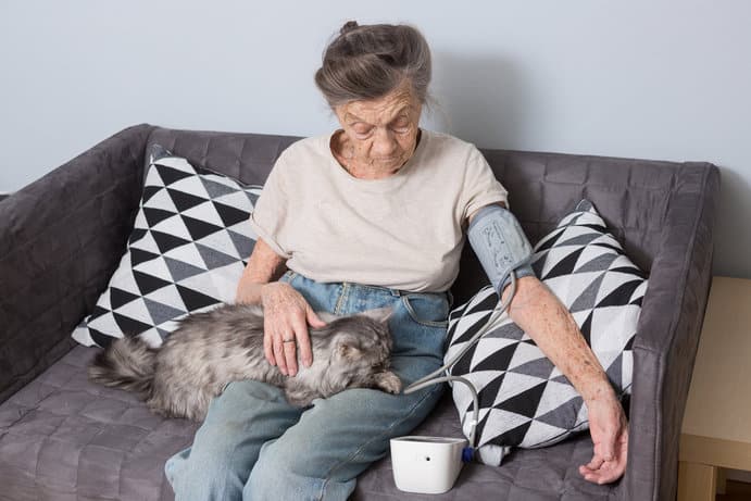 Rentnerin mit Katze beim Blutdruck messen