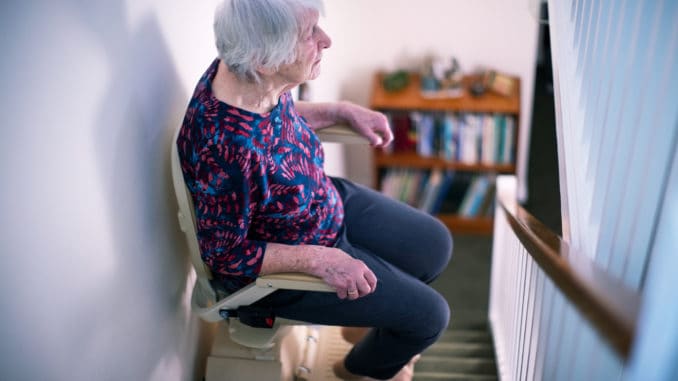 Seniorin sitzt auf dem Treppenlift