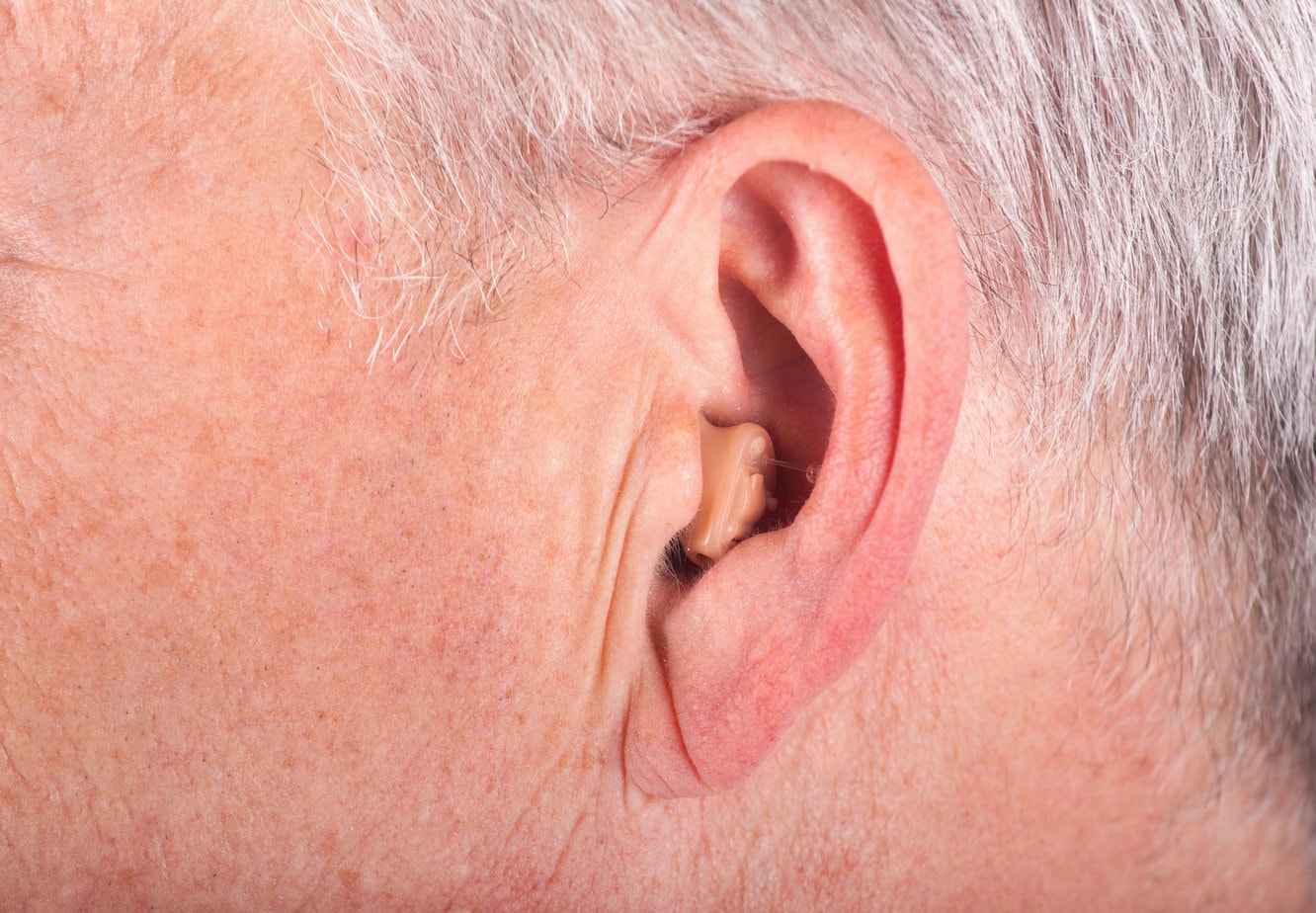 Mini Höhrgerät im Ohr eines Mannes